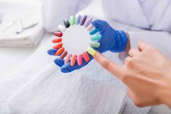 Cropped view of woman choosing color of nail polish near set of artificial nails — Stock Photo