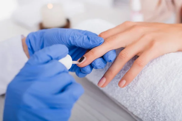 Abgeschnittene Ansicht der Maniküre, die Nagellack auf den Fingernagel des Kunden aufträgt, verschwommener Vordergrund — Stockfoto