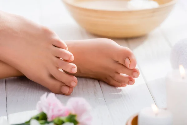 Vista cortada de pés femininos com pedicure pastel rosa na superfície de madeira branca, foreground borrado — Fotografia de Stock