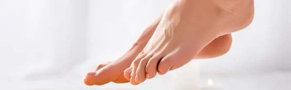 Pieds féminins toilettés avec vernis brillant sur les ongles des orteils sur fond blanc, bannière — Photo de stock