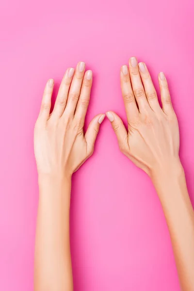 Vista superior de mãos femininas com esmalte pastel em unhas no fundo rosa — Fotografia de Stock