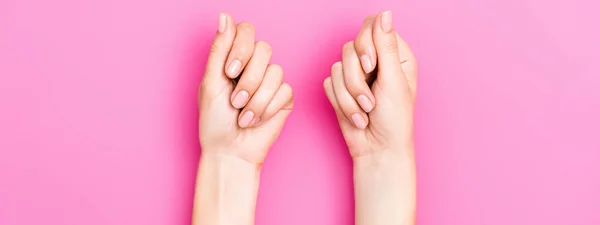 Vue du haut des mains féminines avec émail pastel sur les ongles sur fond rose — Photo de stock