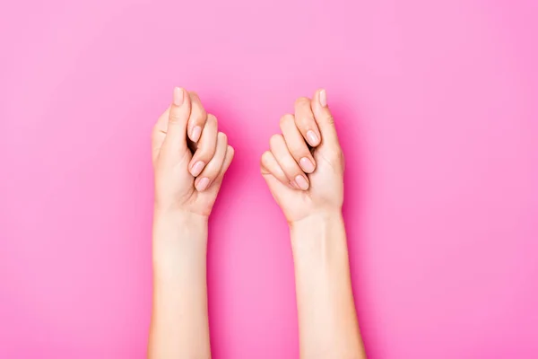Вид зверху на жіночі руки з пастельним лаком для нігтів на нігтях на рожевому фоні — стокове фото