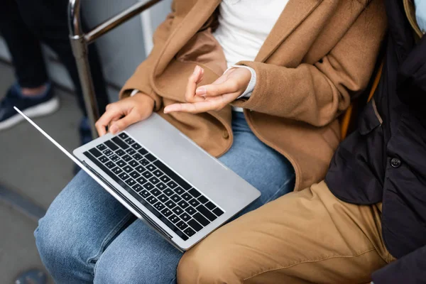 Cropped view of african american woman pointing with finger at laptop near man in subway — Stock Photo