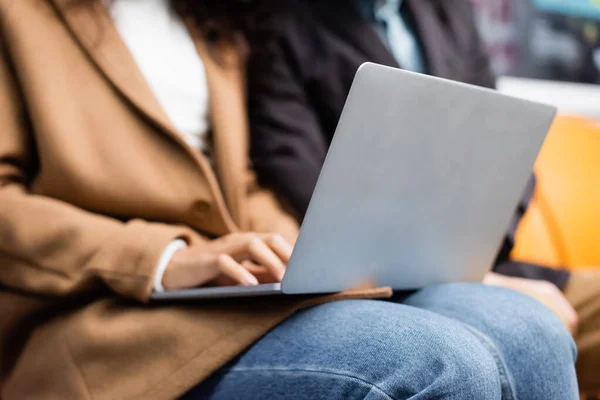 Vista parziale della donna afro-americana utilizzando laptop vicino all'uomo in metropolitana — Foto stock