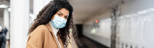 Joven afroamericana mujer en máscara médica en metro, pancarta - foto de stock