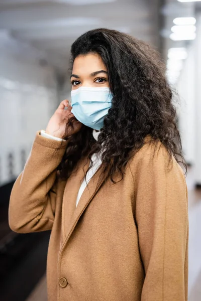 Curly african american woman in medical mask in metropolitan — Stock Photo