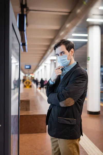 Мужчина в медицинском халате смотрит на камеру на платформе в метро — стоковое фото