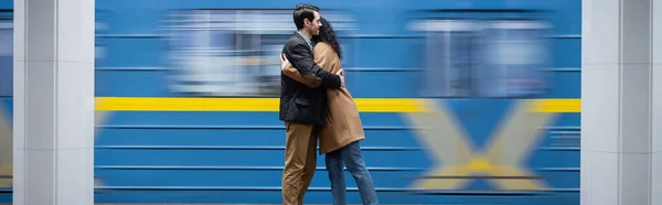 Borrão de movimento de casal interacional abraçando perto do vagão no metrô, banner — Fotografia de Stock