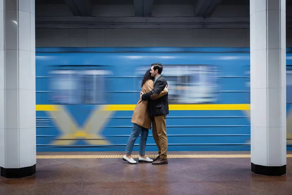 Flou de mouvement de couple interactionnel étreignant près du wagon dans le métro — Photo de stock