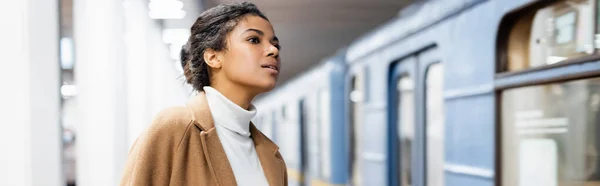 Mujer afroamericana rizada mirando vagón de metro sobre fondo borroso, pancarta - foto de stock