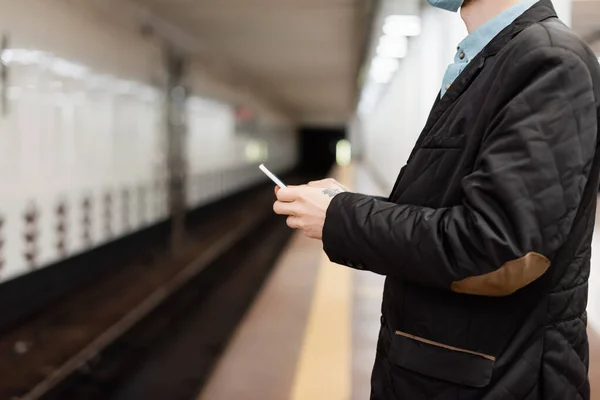 Vue recadrée d'un homme tatoué tenant un smartphone dans le métro — Photo de stock