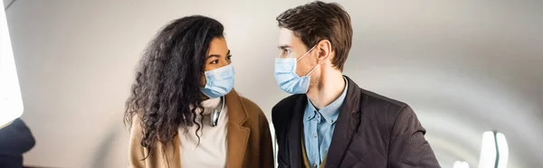 Casal interracial em máscaras médicas olhando um para o outro no metrô, banner — Fotografia de Stock