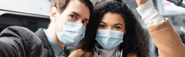 Couple multiculturel dans des masques médicaux dans wagon de métro, bannière — Photo de stock