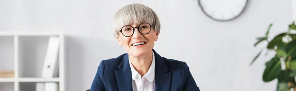Cheerful team leader in glasses smiling in office, banner — Stock Photo