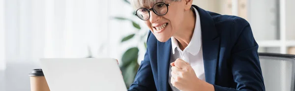 Líder del equipo preocupado en gafas animando mientras mira el ordenador portátil, pancarta - foto de stock