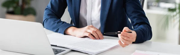 Abgeschnittene Ansicht einer Geschäftsfrau mit Stift in der Nähe von Laptop auf dem Schreibtisch, Banner — Stockfoto