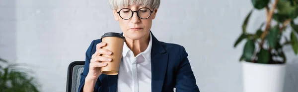 Middle aged team leader in glasses holding paper cup in office, banner — Stock Photo