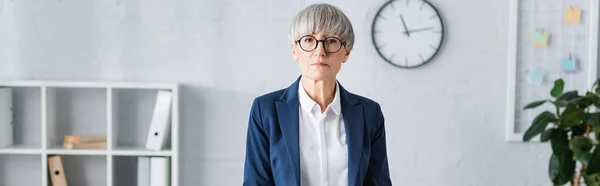 Middle aged team leader in glasses and suit looking at camera, banner — Stock Photo