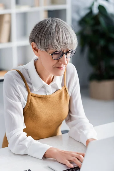 Mature chef d'équipe tapant sur ordinateur portable dans le bureau — Photo de stock