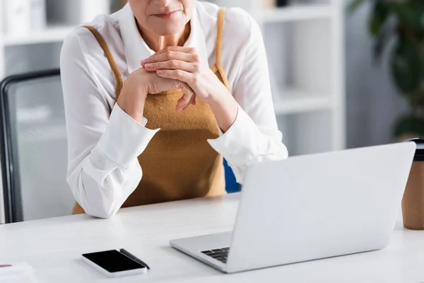 Visão cortada de líder de equipe madura sentado na mesa com gadgets — Stock Photo