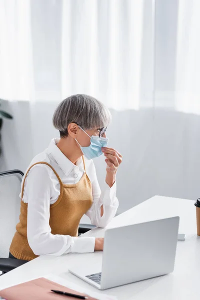 Chef d'équipe d'âge moyen en lunettes ajustement masque médical au bureau — Photo de stock