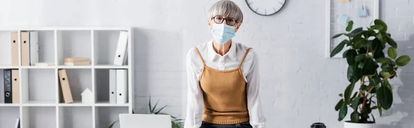 Middle aged team leader in glasses and medical mask looking at camera, banner — Stock Photo