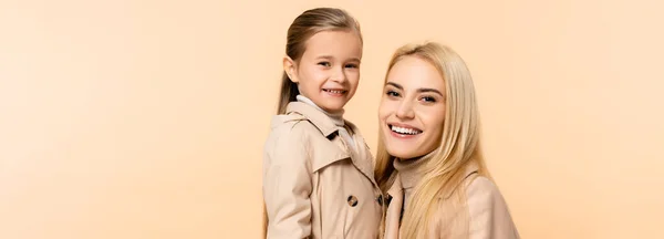 Cheerful blonde mother and daughter isolated on beige, banner — Stock Photo