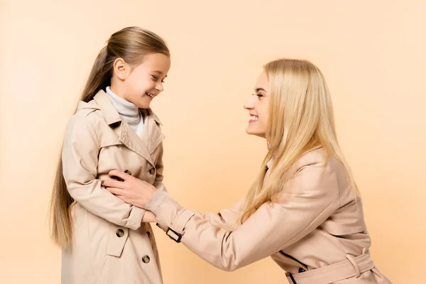 Cheerful blonde mother tickling happy daughter isolated on beige — Stock Photo