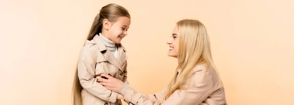 Cheerful blonde mother tickling happy daughter isolated on beige, banner — Stock Photo