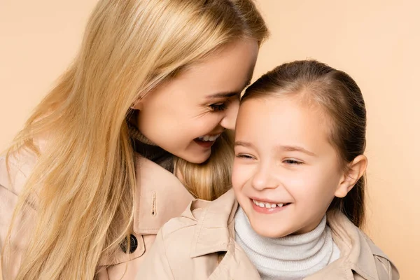 Cheerful blonde mother and happy daughter laughing isolated on beige — Stock Photo