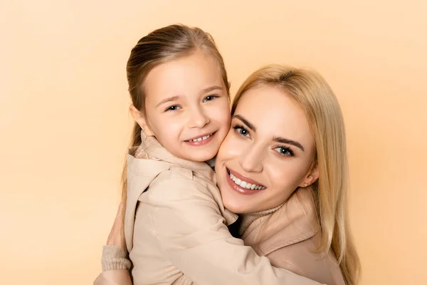 Freudige blonde Mutter und Tochter umarmen sich isoliert auf beige — Stockfoto