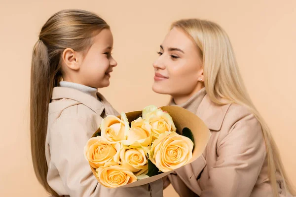 Gelbe Rosen in den Händen des Kindes nahe der Mutter am 8. März und verschwommener Hintergrund isoliert auf beige — Stockfoto