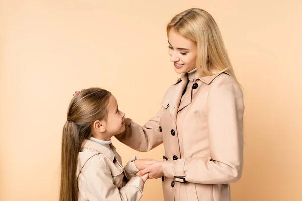 Fürsorgliche Mutter und Tochter halten sich an den Händen und schauen einander isoliert auf beige an — Stockfoto