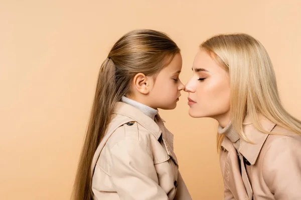 Side view of mother and kid touching noses isolated on beige — Stock Photo