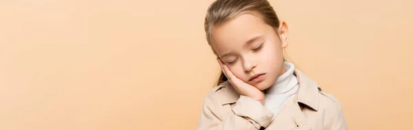 Enfant endormi avec les yeux fermés en trench coat isolé sur beige, bannière — Photo de stock