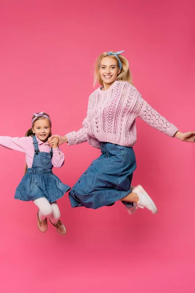 Mutter und Kind lächeln und springen auf rosa — Stockfoto