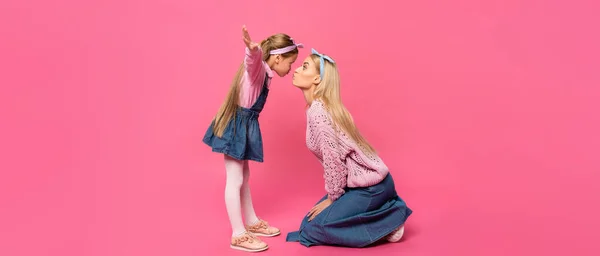 Vista lateral das bochechas puffing criança enquanto de pé com as mãos estendidas perto da mãe em rosa, banner — Fotografia de Stock