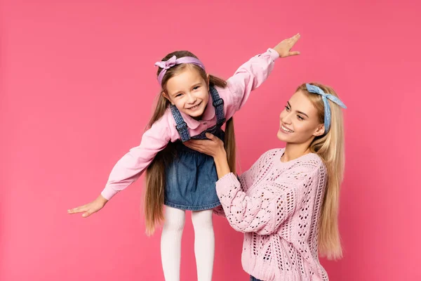 Madre feliz hija de apoyo con las manos extendidas aisladas en rosa - foto de stock