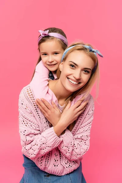 Fröhliches Kind umarmt glückliche Mutter isoliert auf rosa — Stockfoto