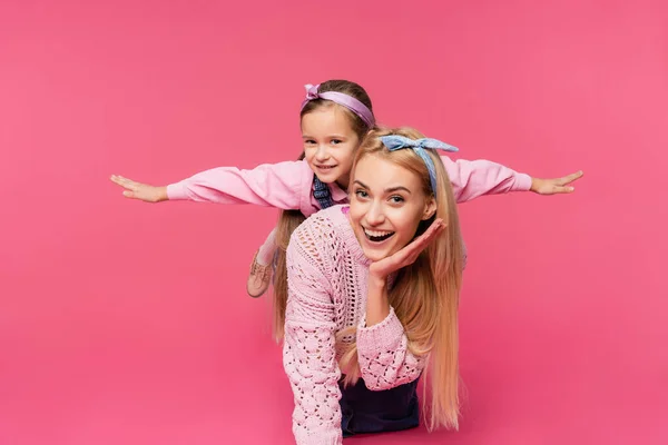 Mother smiling near daughter with outstretched hands isolated on pink — Stock Photo