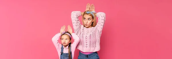 Mutter und Tochter basteln Hasenohren mit Händen isoliert auf rosa, Banner — Stockfoto