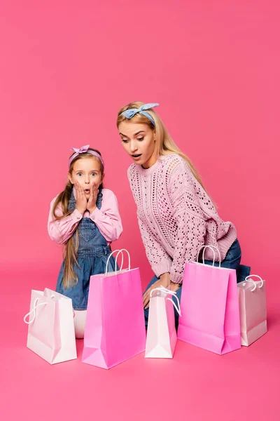 Scioccato madre e figlia guardando borse della spesa su rosa — Foto stock