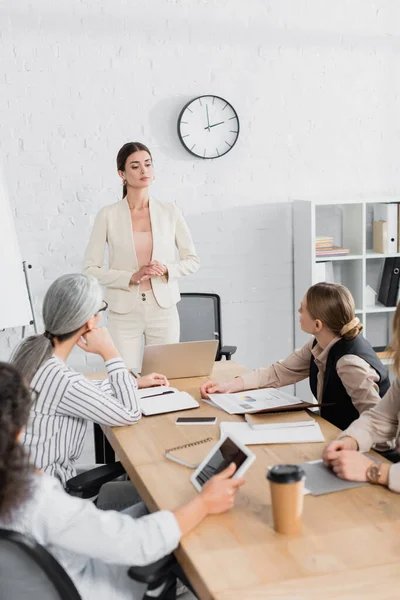 Team leader standing near multiethnic businesswomen during meeting in office — Stock Photo