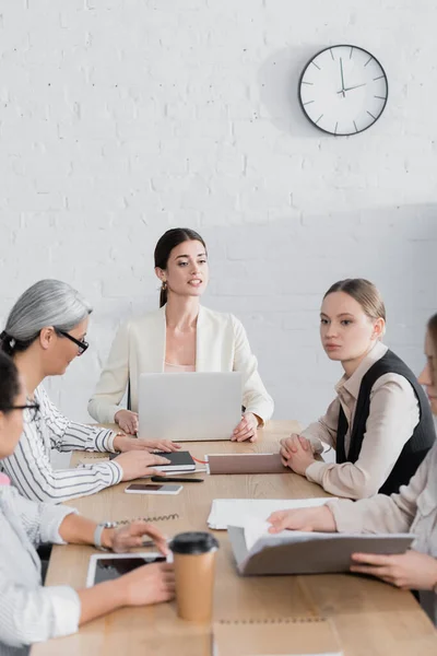 Erfolgreicher Teamleiter blickt bei Treffen auf Geschäftsfrauen in der Nähe multikultureller Kollegen — Stockfoto