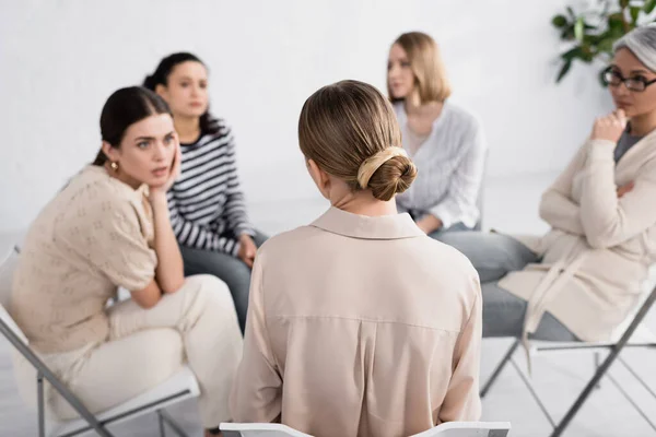 Back view of woman sitting on chair near multicultural female group during seminar — Stock Photo