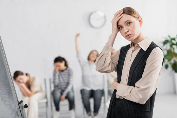 Worried young speaker near businesswomen during seminar on blurred background — Stock Photo