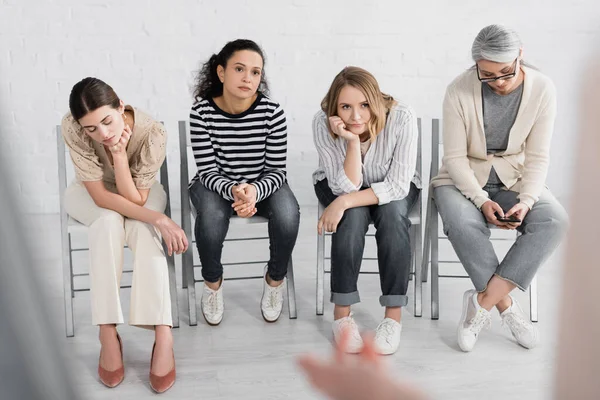 Cansadas empresarias multiculturales sentadas en sillas durante el seminario - foto de stock