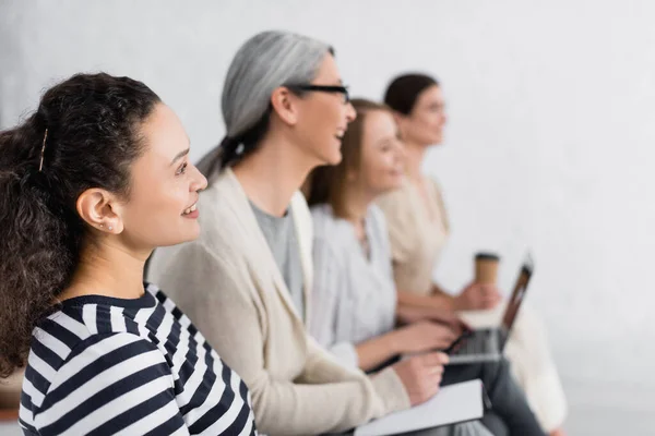 Happy african american businesswoman smiling near group of women during seminar — Stock Photo