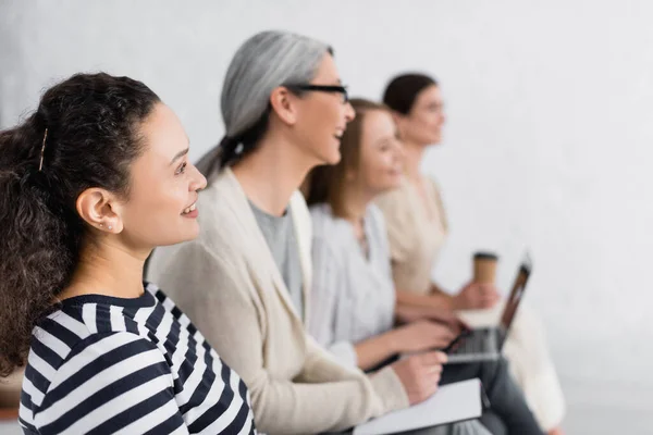 Feliz afroamericana empresaria sonriendo cerca grupo de mujeres durante seminario - foto de stock